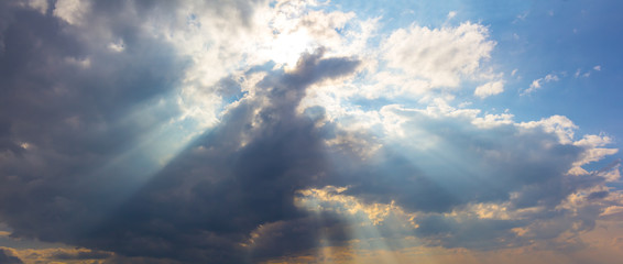 Naklejka na ściany i meble sun rays push through a dense cumulus clouds, beautiful natural sky background