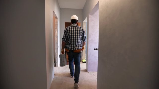 repairman walks in the apartment during the construction