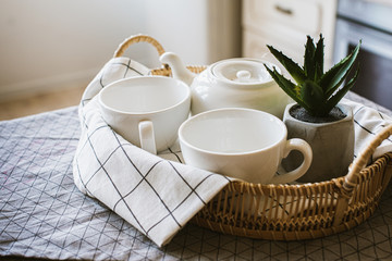 Tea set, including two tea cups, tea kettle in a wicker basket, table colors. preparation for morning tea 