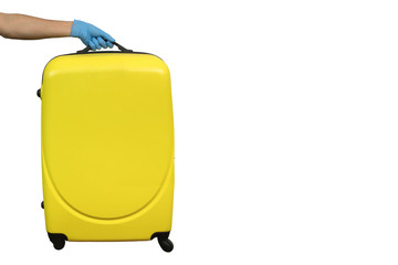 Fototapeta na wymiar man in a latex blue glove holds a yellow suitcase in his hand on a white background. pandemic journey