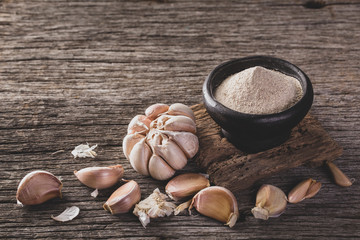 garlic and garlic powder on old wood, close up image