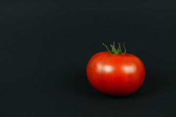 bright red tomato on a black background with the right side