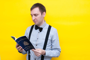 side view of handsome confident man in blue shirt and suspender reading usa constitution and independence declaration on yellow background with copy space