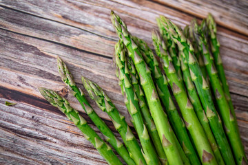 Row of fresh organic green asparagus from farm market on an old wooden background with place for text. Healthy food concept. Top view. Copy space.