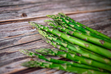 Row of fresh organic green asparagus from farm market on an old wooden background with place for text. Healthy food concept. Top view. Copy space.