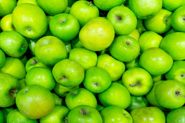 A bunch of light green apples are close-up on a shelf in the store. The concept of the beginning of summer, happiness, useful natural vitamins.