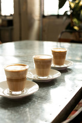 several transparent cappuccino glasses standing on the table next to each other in line, vertical frame, side view. The concept of a charge of energy for work.