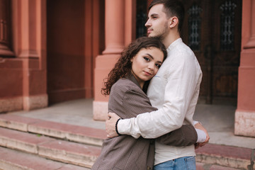 Portrait of beautiful young couple walking outdoors. Hansomen man with attractive woman in the city. Moman with curly hair. Space for text