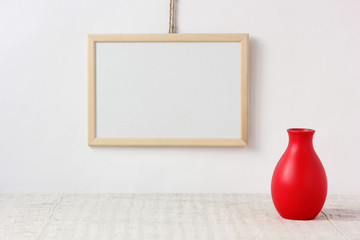 mockup. empty wooden frame with space for copying and a small red vase.