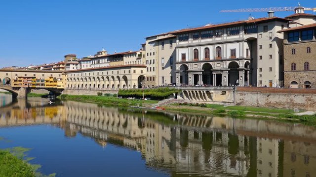 Walking in front of Uffizi and Ponte Vecchio, medieval stone bridge over of Arno river at clear summer day in Florence, Italy.