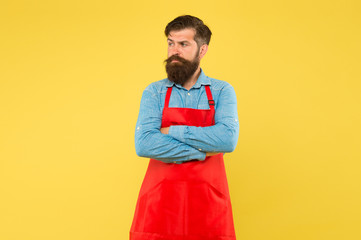 Professional cookery. his new business. guy in shop assistant uniform. serious man with red apron on yellow background. Confident expression. Handsome male barista is working. mature bartender