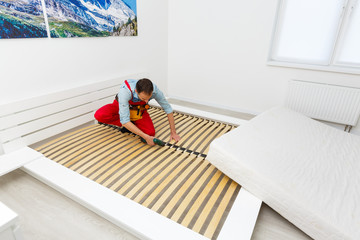 Man's hands working with a hex key. Assembling furniture. Wooden plank of a bed. Close up.