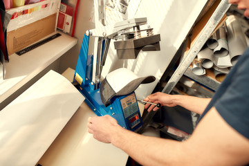 Real designs. Real results. Cropped shot of man using machine for printing on baseball cap in workshop. Printing on clothing and textiles concept