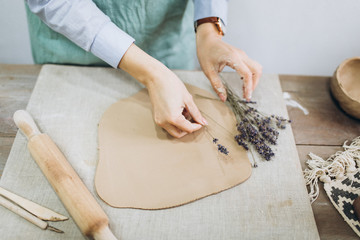 The potter's hands are shaped a cup from a clay. The process of creating pottery. The master ceramist works in his studio. Close-up, only hands. Crockery from clay own hands.	