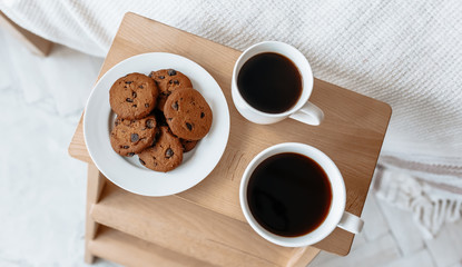 Breakfast in bed. Hot coffee with oatmeal cookies with chocolate on a wooden tray.