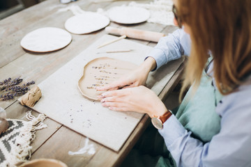 The potter's hands are shaped a cup from a clay. The process of creating pottery. The master ceramist works in his studio. Close-up, only hands. Crockery from clay own hands.	