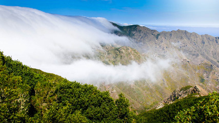 Landscape of clouds flying over the mountain valley on bright sunny day