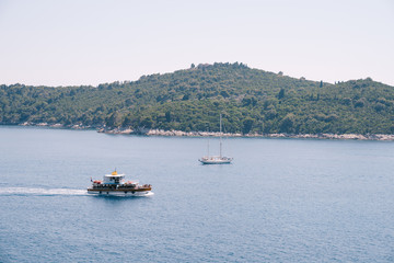 Fototapeta na wymiar Lokrum is a small island in the Adriatic Sea, near Dubrovnik, Croatia. Tourist ships sail past the island, a sailing yacht moored near the coast.