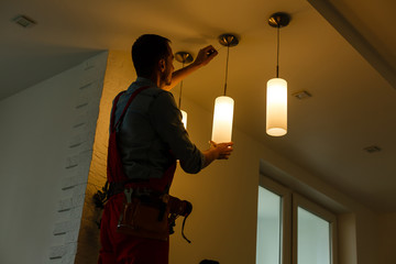 Electrician is installing and connecting a lamp to a ceiling.