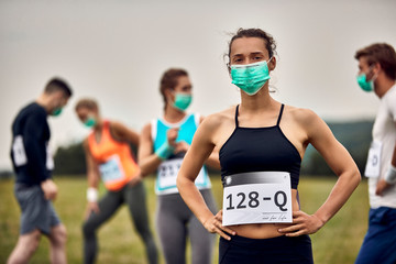 Naklejka premium Young sportswoman wearing face mask while participating in marathon race during coronavirus epidemic.