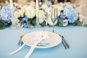 banquet table is decorated with plates, cutlery, glasses, candles and flower arrangements