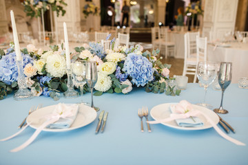 banquet table is decorated with plates, cutlery, glasses, candles and flower arrangements