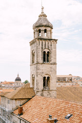 Fototapeta na wymiar The bell tower of the Dominican monastery on the background of modern Dubrovnik, Croatia.