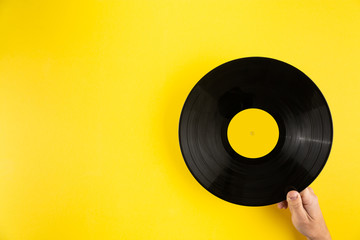Hand holding vinyl record on abstract yellow background