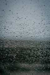 Raindrops on glass, view from the window, heavy rain, bad weather, loneliness, isolation. The texture of the wet surface, background, beautiful wallpaper. Nature is crying.
