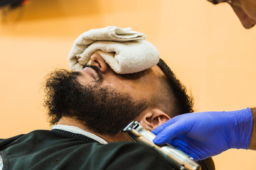 Fototapeta premium Closeup of a latex gloved hand, working the beard of a bearded man.