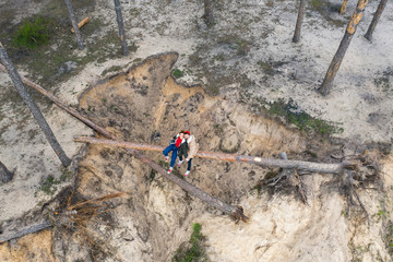 young beautiful sits on a tree over a cliff