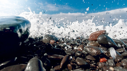 Closeup image of powerful ocean waves breaking and rolling tones and rocks on the sea beach