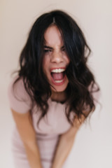 Portrait of angry brunette screaming at camera. Lady in beige outfit posing emotionally