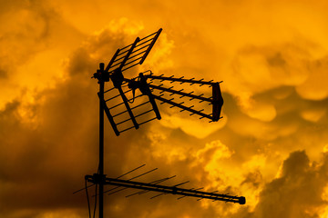 TV antennas and arrays with golden sunset sky and clouds