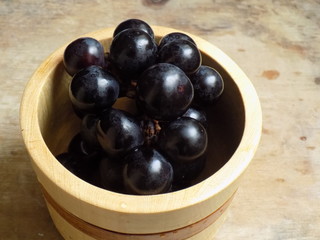 Uvas negras en recipiente de madera