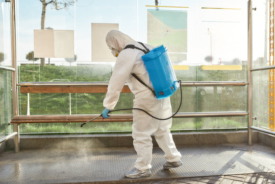 Save a life. Sanitization, cleaning and disinfection of the city due to the emergence of the Covid19 virus. Man in protective suit and mask at work near the bus stop
