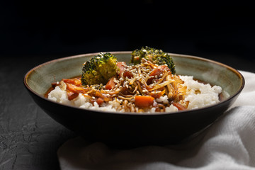 Thai style rice with fried vegetables and soy sauce on dark background