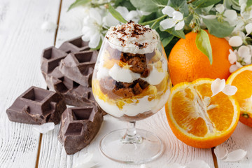 creamy trifle in beautiful glasses and cut fresh ripe fruit on white wooden background - healthy eating concept