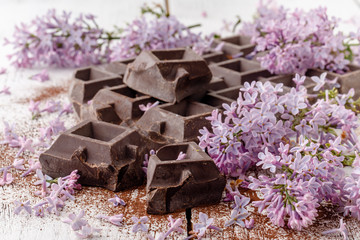 Dark chocolate on table with liliac flowers