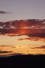 Luminous shades of yellow and orange streak the skies over the Mountains during sunset.