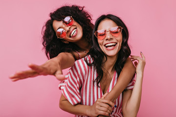 Unrestrained merriment of two girls captured on snapshot. Photos in pink shades of brunettes with...