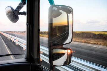 In cockpit of a truck at dawn. Large rear-view mirrors