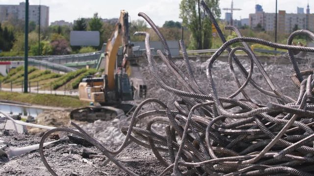 Bulldozer in operation on the construction site. Demolition of the bridge. Metal wires in foreground.