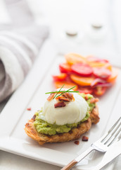 Avocado toast with poached egg and tomato salad  on a a marble top for brunch