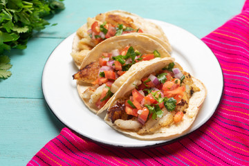 Mexican fish tacos also called Baja with fresh sauce on turquoise background