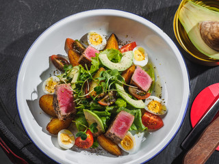 Salad with raw meat avocado eggs cherry in enamel plate