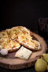 Pear and blue cheese toast with rosemary and honey on a dark and rustic background
