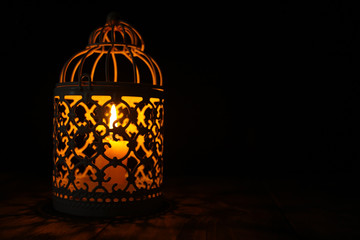 Candle lanterns on a rustic wooden table that lights up as a light source at the dark night