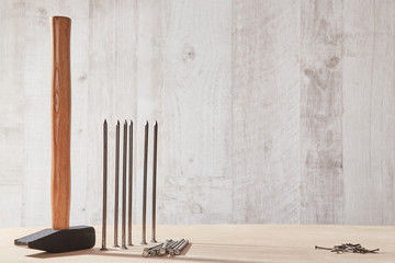 Hammer tool on wooden table. Different sizes of tacks. Renovation and construction site. Copy...