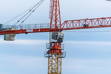 close-up of tall orange crane on the construction of a new house against the blue sky.